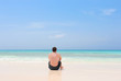 Young man sitting alone on a tropical beach