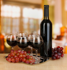 Red wine in glass and bottle on room background