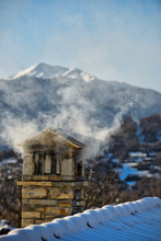 A Mountain House Roof With Smoking Chimney