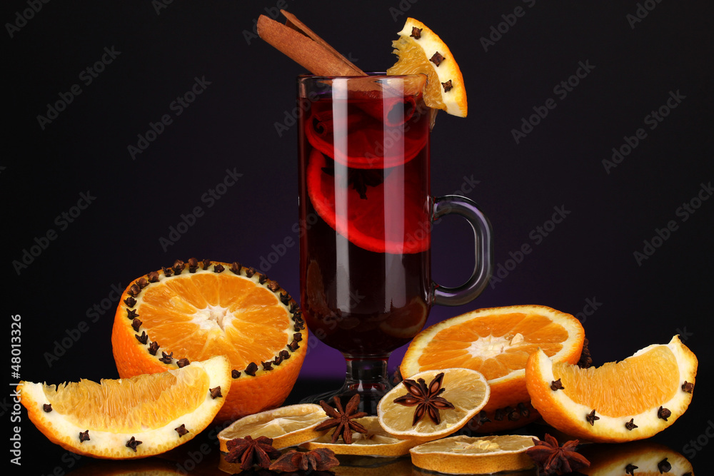 Fragrant mulled wine in glass with spices and oranges around