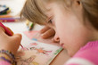 © philidor - Close up of a girl with down syndrome drawing.