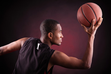 Wall Mural - young male basketball player against black background