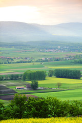 Poster - Green meadow under sunset sky with clouds