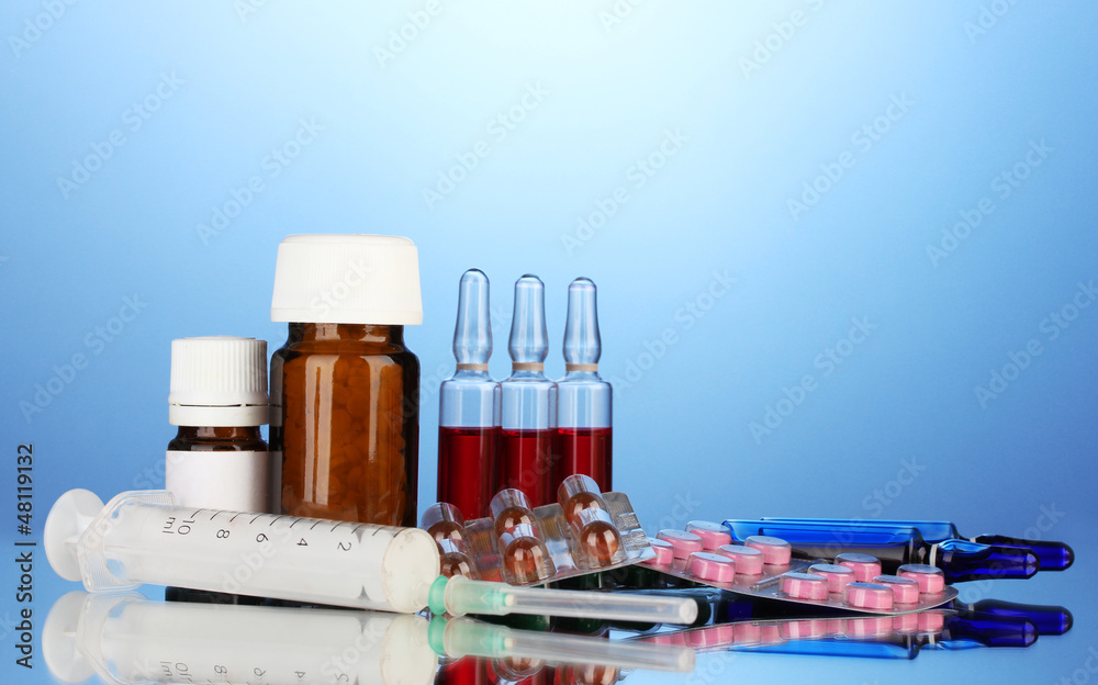 medical ampules, bottles, pills and syringes on blue background