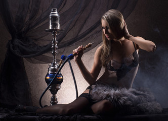 Wall Mural - A young and sexy blond woman smoking a hookah