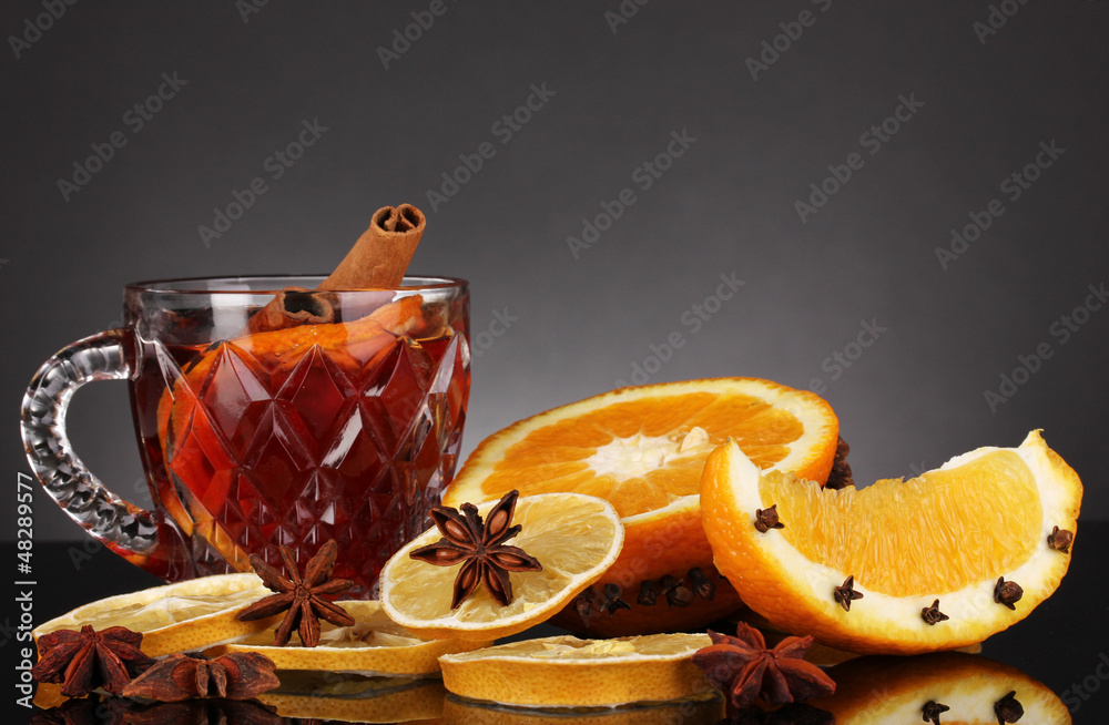 Fragrant mulled wine in glass with spices and oranges around