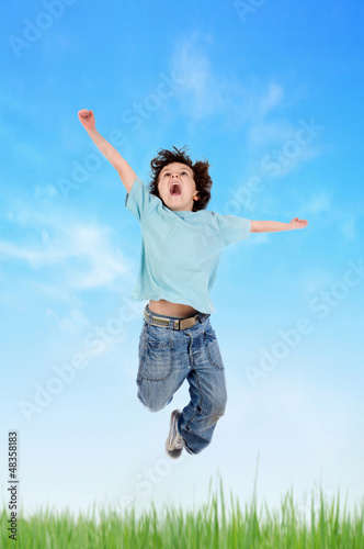 Naklejka ścienna Adorable child jumping on the meadow