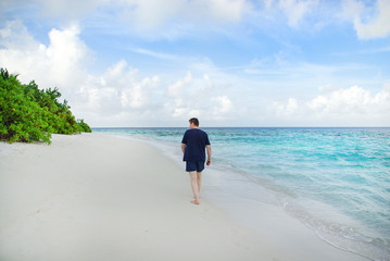 Wall Mural - Young man on white sand beach on Maldives