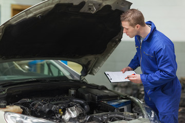 Poster - Mechanic with clipboard examining car engine