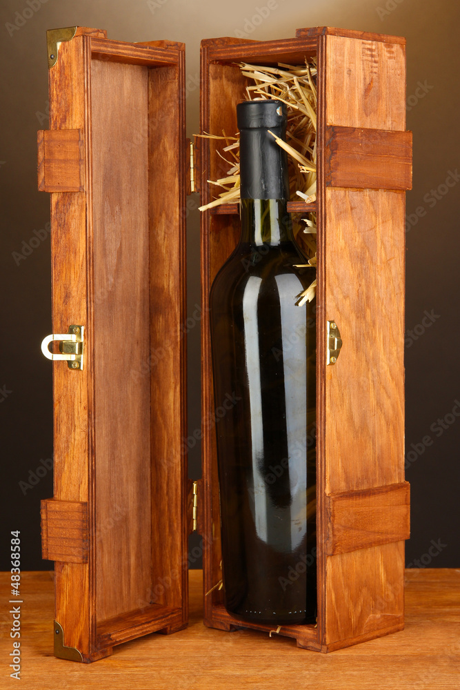 Wooden case with wine bottle on wooden table on brown
