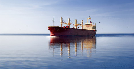 Wall Mural - General cargo ship with cranes sailing in a still sea water. Clear blue sky. Panoramic view. Freight transportation, nautical vessel, global communications, industry, carrying, logistics, commerce