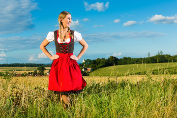 Junge Frau auf der Wiese und trägt Dirndl