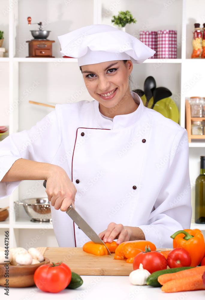 Young woman chef cooking in kitchen