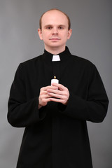 Wall Mural - Portrait of young Pastor holding candle in his hand,on gray
