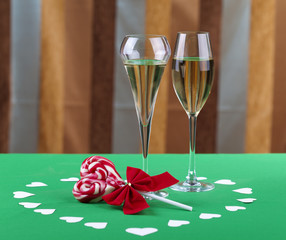 Two glases of champagne next to a heart shape candy