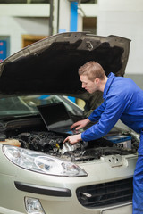Poster - Auto mechanic with laptop repairing car