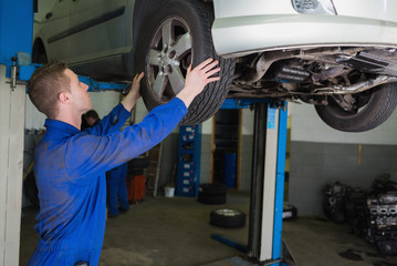 Poster - Auto mechanic examining car tire