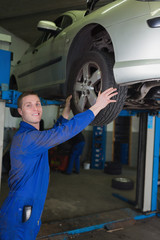 Poster - Car on hydraulic lift as mechanic examining tire