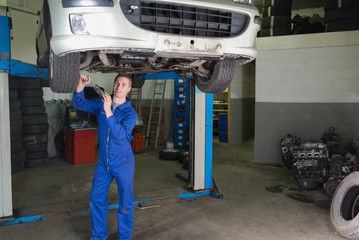Poster - Mechanic working under raised car