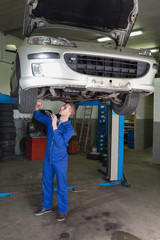 Poster - Mechanic working under raised car in garage
