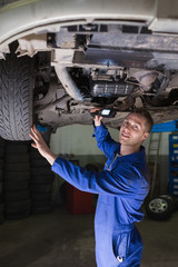 Poster - Male car mechanic examining vehicle