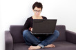 © Edler von Rabenstein - Woman sitting with laptop relaxing on the sofa