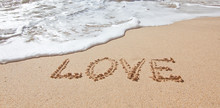 The Word Love In The Sea On The Beach In Valentine Day. Closeup.
