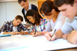 © goodluz - Group of teenagers in class writing an exam