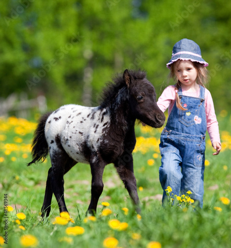 Naklejka dekoracyjna Child and foal in the field at spring.