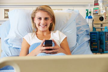 Teenage Female Patient Using Mobile Phone In Hospital Bed