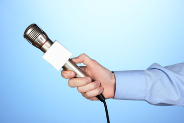 Male hand with microphone on blue background