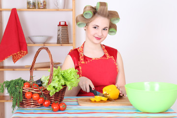 Wall Mural - young housewife cutting yellow pepper in the kitchen