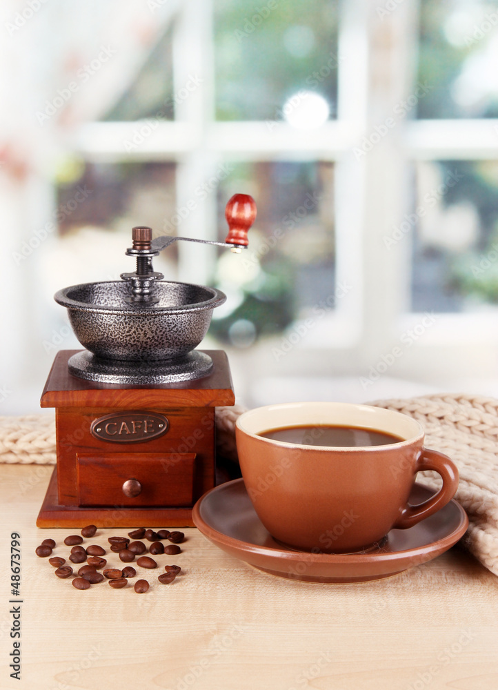 cup of coffee with scarf and coffee mill on table in room