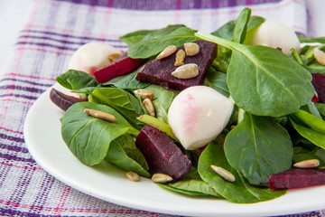 Fresh salad with roasted beets, spinach, mozzarella and seeds