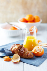 Wall Mural - Croissant, mandarins and mandarin juice on kitchen table