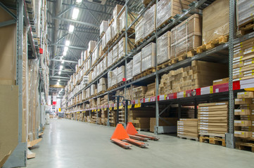 Rows of shelves with huge cardboard boxes and orange storage car