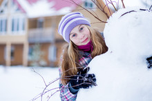 Teenager Girl Making Snowman Outdoors  In Front Of House