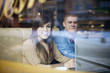 © gpointstudio - Young couple using laptop in coffee shop