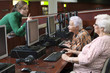 © GM Visuals/Blend Images - Hispanic teacher helping senior students in computer lab