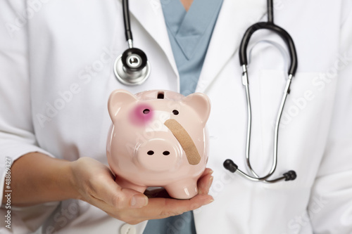 Tapeta ścienna na wymiar Doctor Holding Piggy Bank with Bruised Eye and Bandage