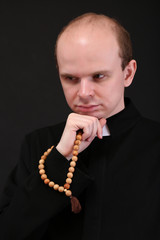 Wall Mural - Young pastor with wooden rosary, isolated on black