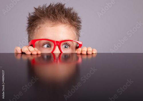 Plakat na zamówienie Five years old little cute boy hiding behind a table
