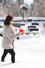 Mid Aged Woman With Candle On Snowy Cemetery