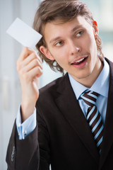 Business man holding a blank business card indoors at his office