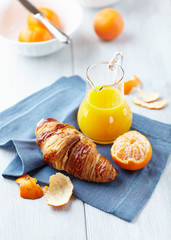 Wall Mural - Croissant and mandarin juice on a blue napkin