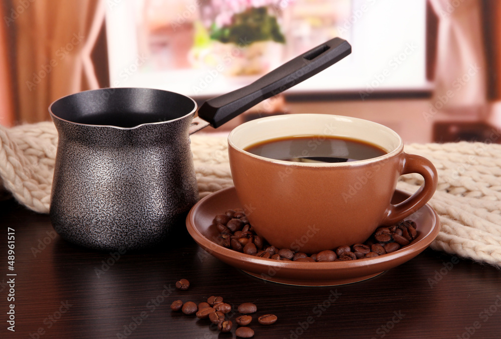 cup of coffee with scarf and coffee maker on table in room