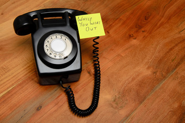 Black retro telephone with reminder note