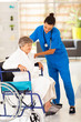 friendly caregiver helping senior woman on wheelchair
