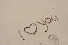 Conceptual Handwritten Love You Text In Sand