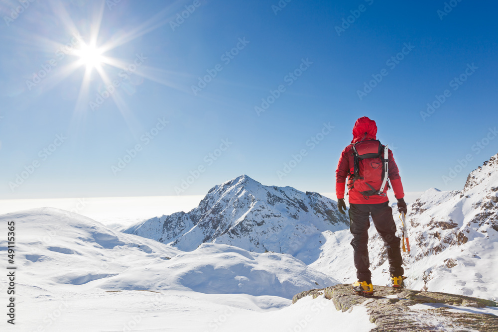 Mountaineer looking at a snowy mountain landscape - obrazy, fototapety, plakaty 